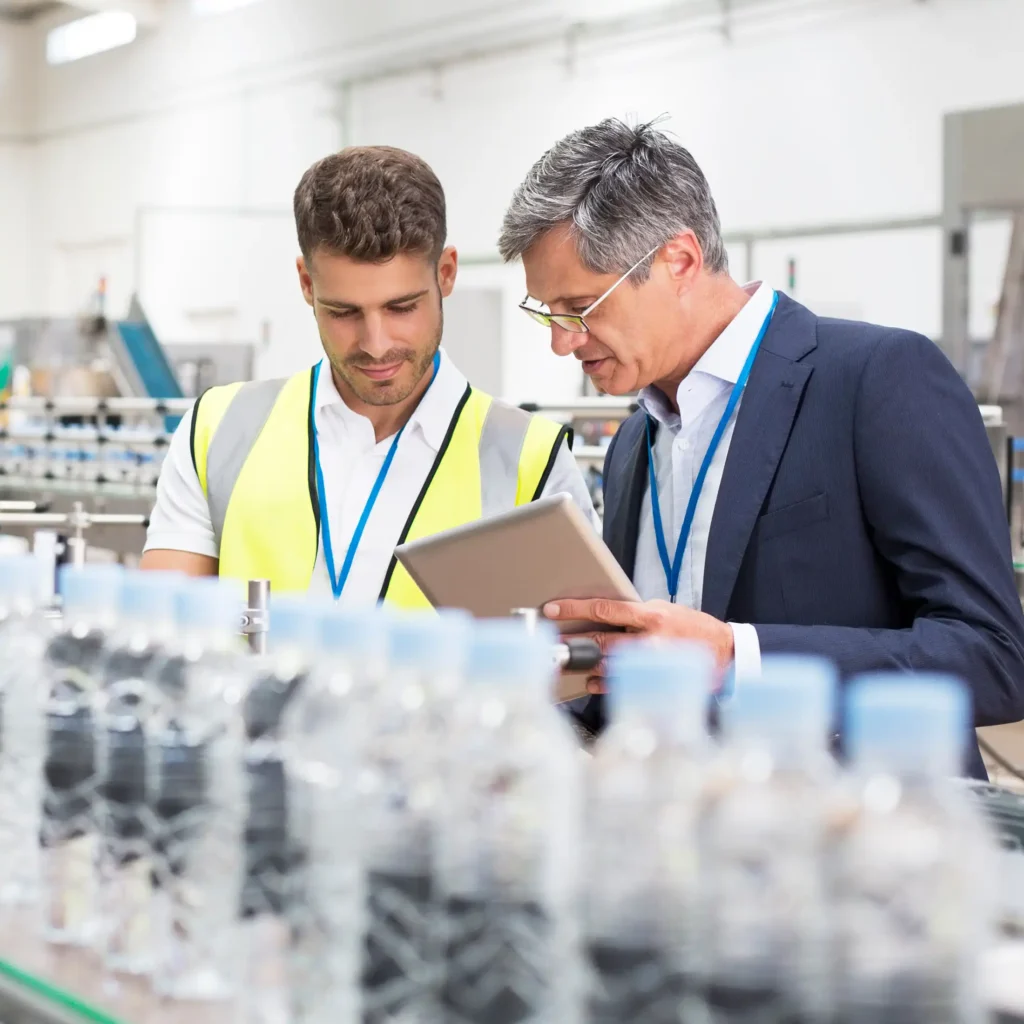 Supervisor and manager watching plastic bottles on conveyor belt